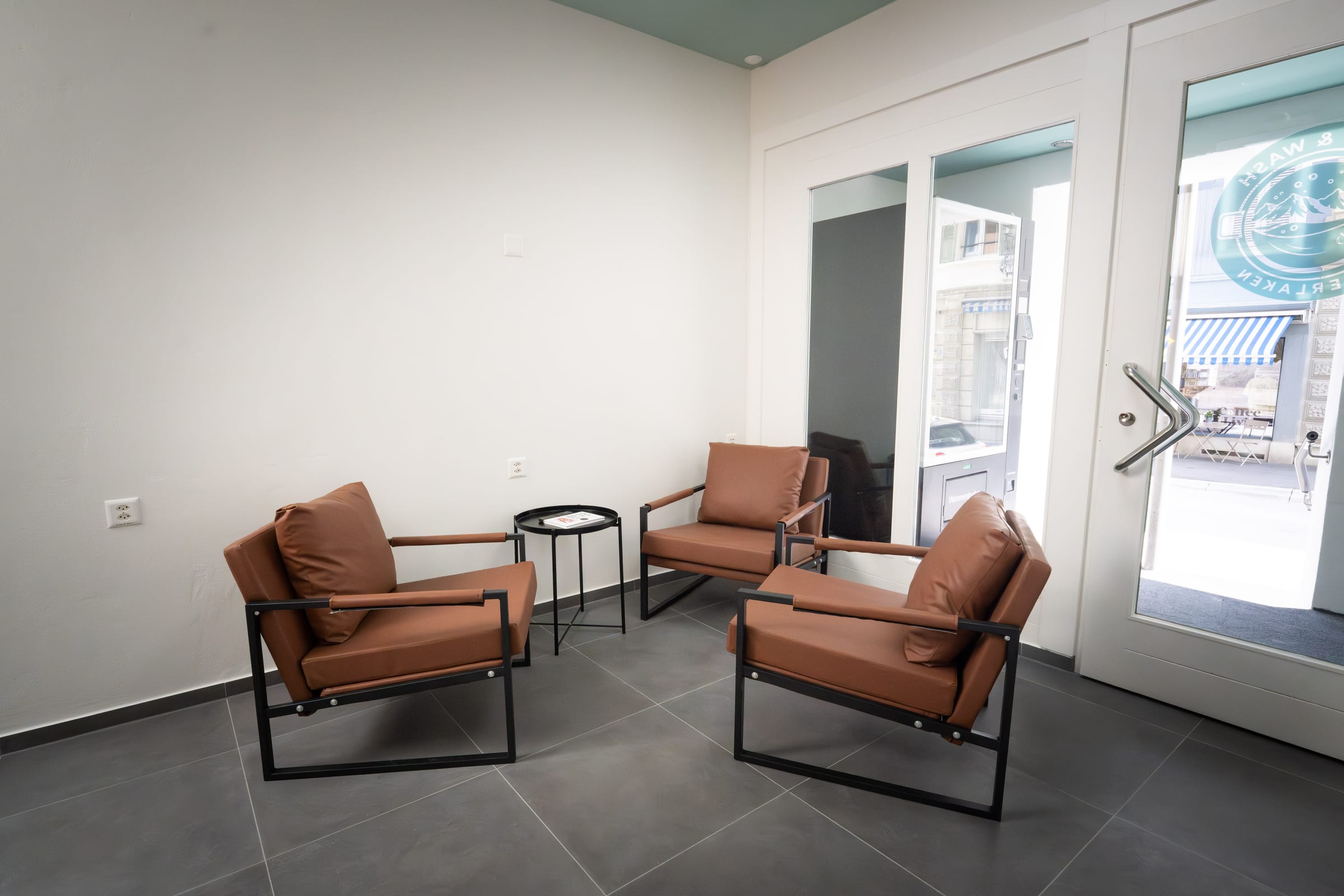Gemütliche Sitzecke mit Ledersesseln im Grab & Wash Waschsalon Unterseen