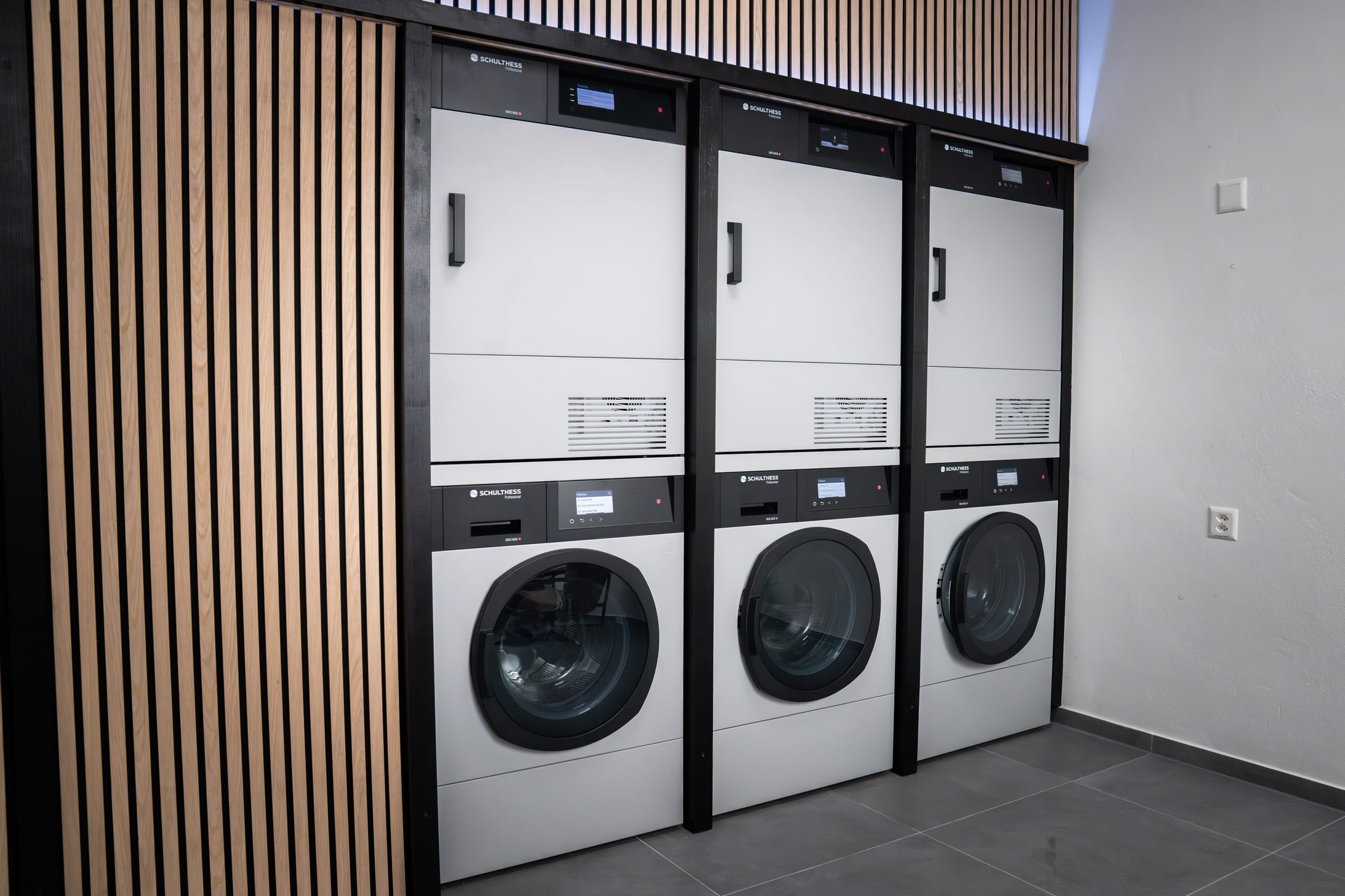 Innenansicht des Grab & Wash Waschsalons in Unterseen mit drei Schulthess Waschmaschinen und Tumblern