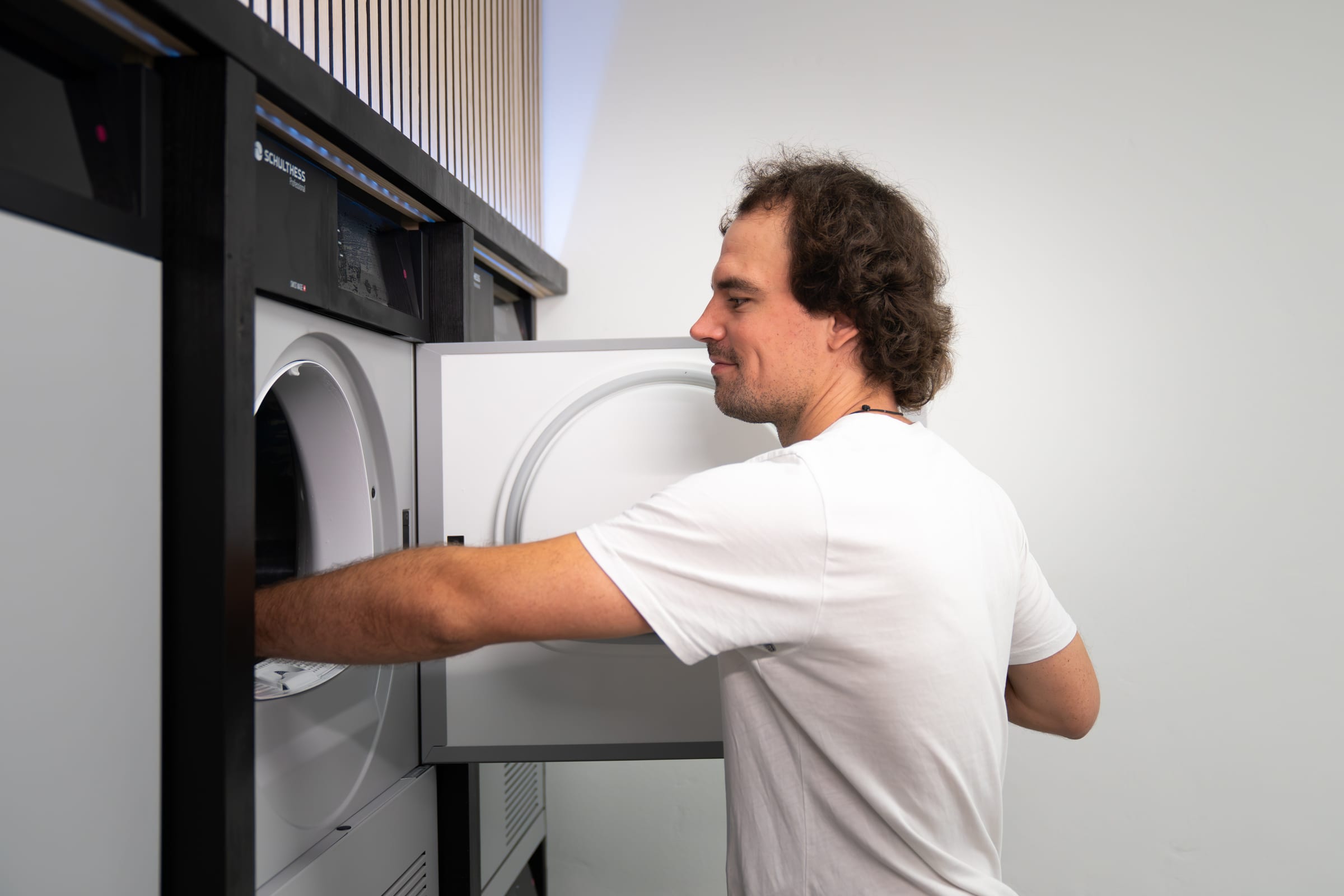 Person an der Waschmaschine im hellen, modernen Waschsalon Grab & Wash in Unterseen